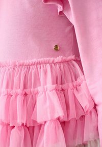 Roza obleka z gladkim zgornjim delom in večplastno krilo z nabranim tulom. Zlati elementi pri pasu dodajo dekorativno podrobnost.