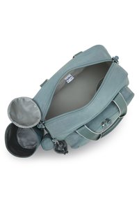 Light teal duffel bag with a zipper closure, adjustable straps, and multiple compartments, including a round side pocket and fur charm.
