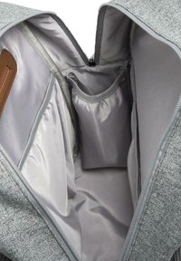 Interior de mochila de tela gris con múltiples compartimentos, incluyendo un bolsillo con cremallera y secciones acolchadas para organización y almacenamiento.