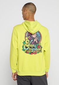 Hoodie jaune vif avec un graphique décoratif au dos, entouré d'une bordure florale et du texte "Vans original Hope for Waves."