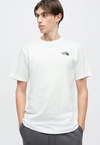 Λευκό βαμβακερό μπλουζάκι με στρογγυλή λαιμόκοψη και κοντά μανίκια. Φέρει μαύρο λογότυπο τυπωμένο στο πάνω αριστερό μέρος του στήθους. Ομαλή υφή.