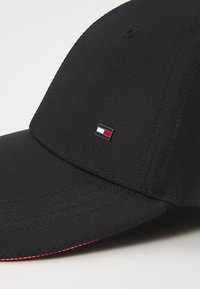 Cappellino da baseball nero con visiera curva e piccolo logo rettangolare bianco, rosso e nero centrato sul pannello frontale.