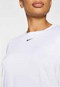 Λευκό αθλητικό μπλουζάκι με στρογγυλή λαιμόκοψη, κοντά μανίκια και μαύρο λογότυπο Nike Swoosh στο μπροστινό μέρος. Λείο ύφασμ�α, ελαφρύ υλικό.