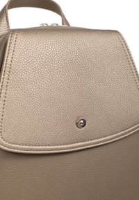 Zaino realizzato in materiale metallico dorato texturizzato, con un robusto cappuccio arrotondato, bordi cuciti e un dettaglio con logo metallico circolare.