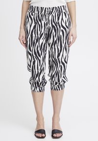 Pantaloni tagliati con stampa zebra bianca e nera, dotati di una vita elastica e polsini arricciati, realizzati in un tessuto leggero.