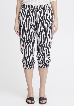 Pantaloni tagliati con stampa zebra bianca e nera, dotati di una vita elastica e polsini arricciati, realizzati in un tessuto leggero.