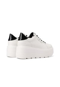 Sneakers bianchi con soletta in gomma testurizzata, accenti in pelle verniciata nera sul tallone e design a punta rotonda. Chiusura con lacci.