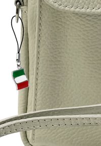 Crème-kleurige leren tas met een gestructureerd oppervlak. Aan de tas hangt een klein Italiaans vlaggetje in rood, wit en groen. Inclusief zilveren hardware-details.