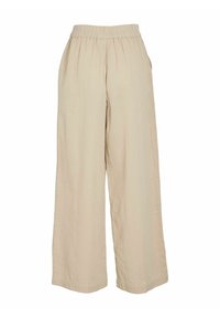 Pantalons larges beiges en tissu texturé, avec une taille élastique, des poches latérales et une coupe décontractée. Pas de motifs ni de métallisation visibles.