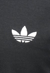 Melnas audums ar ribveida faktūru, virs trim horizontālām svītrām atrodas balts trīs lapu logotips.