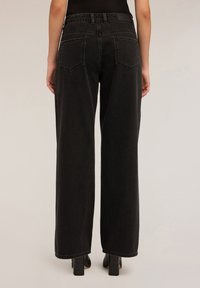 Schwarze weit geschnittene Jeans mit hohem Bund, dezenten Nähten und zwei Gesäßtaschen. Der Stoff ist Denim mit einer glatten Textur.