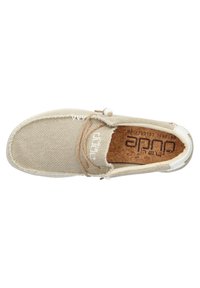 Zapato beige claro hecho de lona texturizada con plantilla de corcho. Presenta un cordón marrón con una cuenta de madera, suela blanca y logo en el lateral.