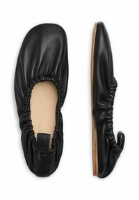 Bailarinas de cuero negro con borde fruncido, punta redondeada y suela de madera plana. Presentan una pequeña pestaña en el talón trasero para facilitar el calzado.