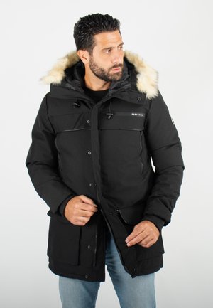 Parka noire avec capuchon en fourrure, dotée de multiples poches frontales, fermeture éclair et boutons-pression. Tissu texturé, conception chaude et durable.