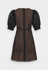 Robe courte noire avec manches courtes bouffantes et superposition en dentelle à découpe géométrique dévoilant une doublure nude en dessous.