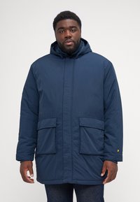 Cappotto imbottito blu navy con cappuccio, dotato di due tasche frontali e polsini elasticizzati. Realizzato in materiale liscio e leggero con chiusura a zip.