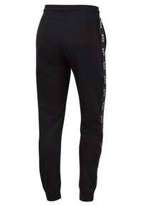 Svarta sweatpants med en avsmalnande passform, elastisk midja och sidostrip som har "NIKE"-logotypen i vitt. Mjuk, blandad bomullstyg.