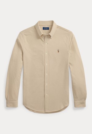 Beige long-sleeve button-up shirt made of cotton, featuring a point collar, subtle texture, and a small embroidered logo on the chest.