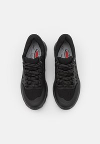 Scarpe sportive nere con tomaia in rete, punta tonda e suola in gomma testurizzata. Presentano lacci grigi e una soletta interna con dettagli rossi.