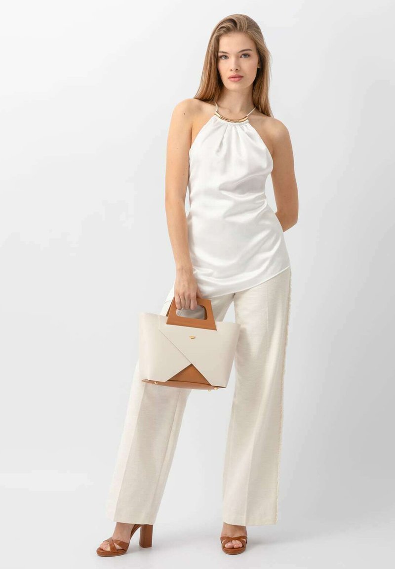 Biały satynowy top na halter, beżowe spodnie na miarę, brązowe sandały na obcasie oraz geometryczna torebka w kolorze kremowym i brązowym z uchwytem.
