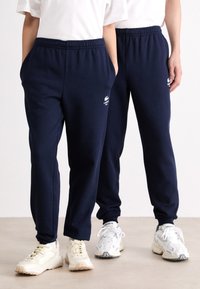 Jūras spēku jogging bikses mīkstā materiāl�ā, ar elastīgu jostasvietu, sānu kabatām un baltu logo detaļu kreisajā augšējā augšstilbā.