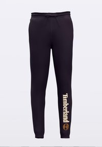 Pantalon de jogging noir en tissu doux avec une taille élastique et un cordon de serrage. L'avant présente le texte "Timberland" en doré accompagné d'un logo.