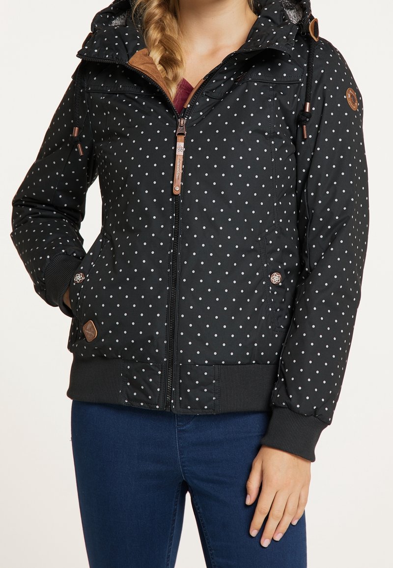 Černá prošívaná bunda s bílými puntíky. Disponuje zipem na přední straně, nastavitelnou kapucí a žebrovanými manžetami. Obsahuje hnědé akcenty z umělé k�ůže.