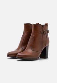 Hnědé kožené kotníkové boty s akcentem v vzhledu krokodýlí kůže, masivním podpatkem a bočním detailem na přezku. Hladký povrch, kulatá špička.