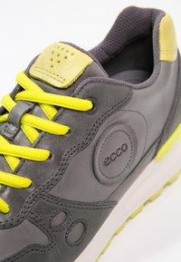 Baskets grises et jaunes avec lacets jaune vif, col rembourré et logo ECCO embossé sur le côté.