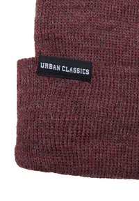 Červený pletený čepice vyrobená z měkkého úpletu s ohrnutým lemem. Na čepici je černý štítek s bílým nápisem "URBAN CLASSICS".
