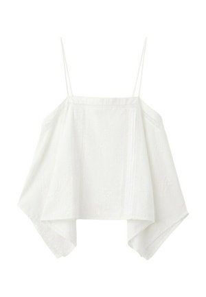 Giovane donna con top bianco senza maniche, shorts di jeans, sandali marroni borchiati, che tiene una borsa verde oliva su sfondo bianco.