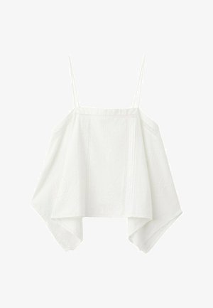 Mladá žena v bielom tielku bez rukávov, riflových šortkách, hnedých sandáloch s cvokmi, drží olivovo zelenú tašku na bielom pozadí.