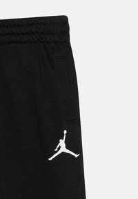 Svarta sweatpants med en vit Jumpman-logotyp på låret, utrustade med resårmidja och sidofickor, tillverkade av mjukt material.