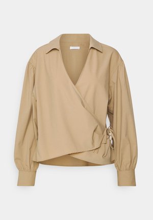 Beżowa koszula zapinana z długimi bufkami, głębokim dekoltem w kształcie V i detalem w postaci wiązania z boku. Gładka tekstura z wyrafinowanym krojem.