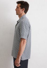 Camicia a maniche corte con bottoni in blu navy e bianco con motivo a stelle, dotata di colletto e vestibilità comoda. Tessuto dalla superficie liscia.