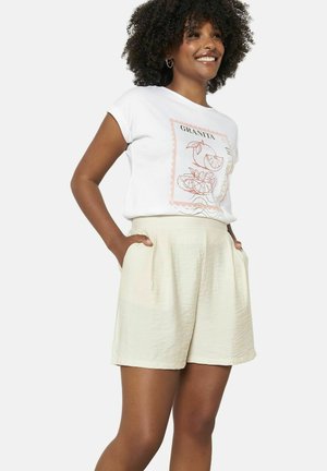 White t-shirt with a peach graphic, paired with light beige shorts. The shorts feature side pockets and a relaxed, textured fabric.