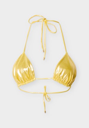 Haut de bikini triangle métallisé doré brillant avec bretelles réglables nouées autour du cou et du dos sur un fond gris uni.
