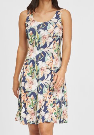 Sukienka bez rękawów do kolan o granatowym tle z kwiatowym wzorem w kolorach brzoskwiniowym, białym i zielonym, noszona przez kobietę, widoczna od szyi do kolan.