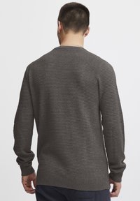 Maglione grigio con texture e motivo intrecciato, maniche lunghe e polsini e orlo a coste, visto da dietro.