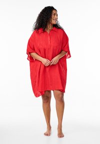 Röd, lättvikts, knälång kaftan med en knappfast krage, vida ärmar och texturerad tyg, barfota mot en enkel vit bakgrund.