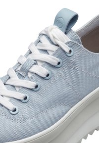 Vaaleansininen kangaskengä, jossa on valkoiset nauhat, pyöreät rei'itykset, teksturoitu pinta ja kiinteä valkoinen pohja, jossa on hieman kohotettu muoto.