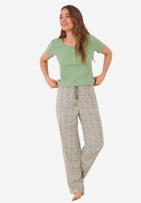 Haut à manches courtes côtelé vert menthe avec trois boutons, associé à un pantalon léger à motifs amples avec un design floral.