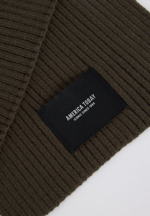 Olive green ribbed knit scarf with a black rectangular tag displaying "AMERICA TODAY" and "ICONIC SINCE 1989" in white text.