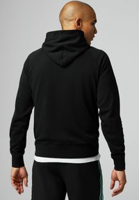 Schwarzer Baumwoll-Hoodie mit Kängurutasche, Raglanärmeln und gefütterter Kapuze. Verfügt über gerippte Bündchen und Saum für eine enge Passform.