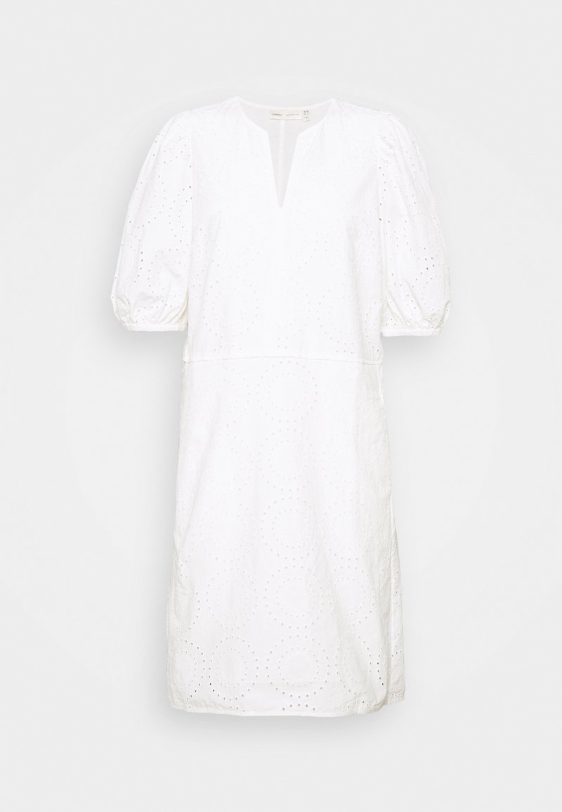 Robe blanche mi-longue aux genoux avec manches courtes bouffantes, encolure en V avec encoche et motif circulaire de broderie ajourée.