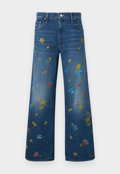 Modré džínsy s širokými nohavicami s viacfarebnými vyšívanými kvetinovými vzormi rozptýlenými na prednej a zadnej strane.