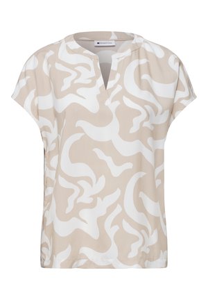 Blouse beige à manches courtes avec motif tourbillon abstrait blanc et encolure ronde avec ouverture en V à l'avant.