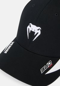 Zwarte baseballcap met een wit geborduurd logo met tanden. Inclusief branding in het wit en rood op de klep. Gestructureerde stof.