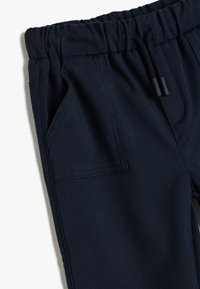 Marineblauwe katoenen blend broeken met een elastische tailleband, verstelbaar trekkoord en zijzakdetails. Gladde textuur met gestikte naden.