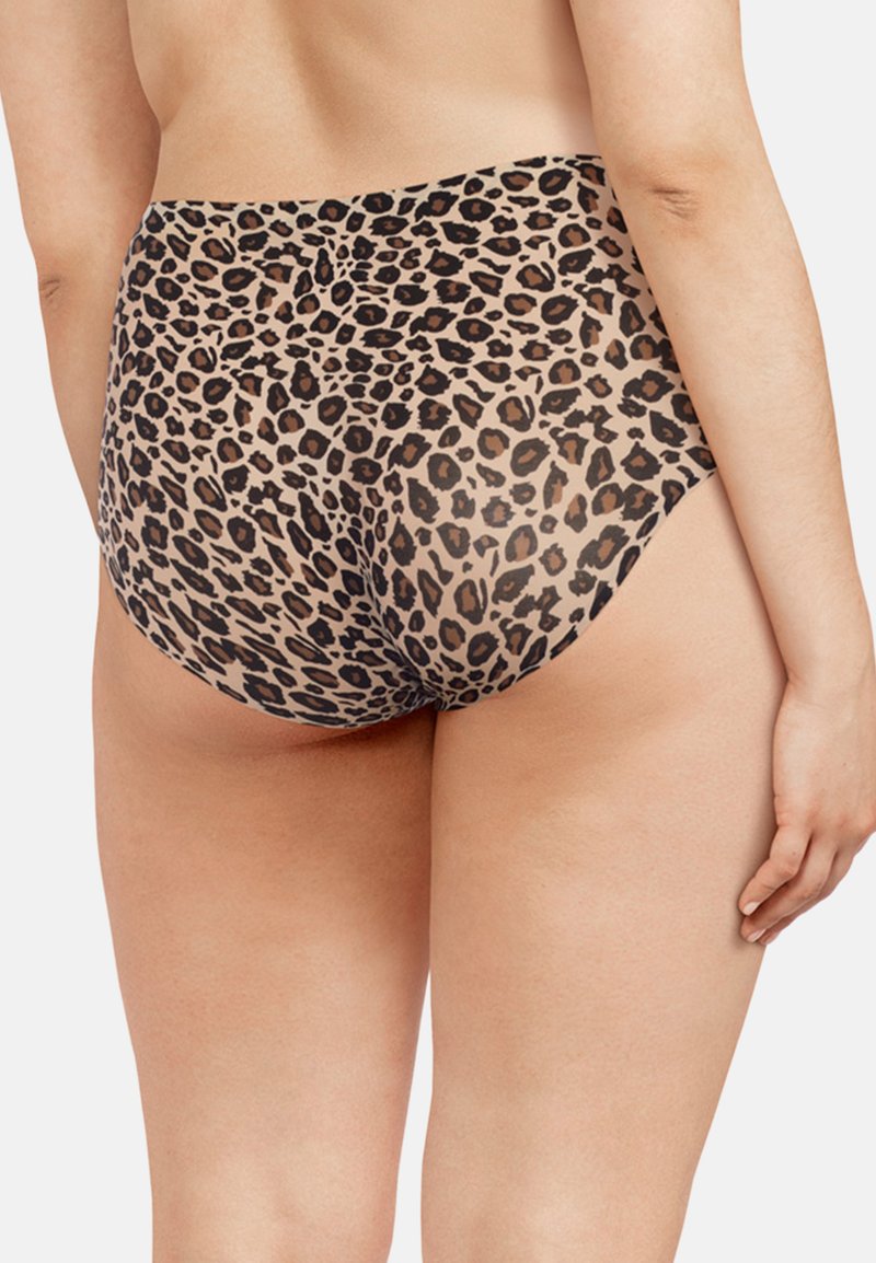 Vrouw met hooggetailleerd ondergoed met luipaardprint, gezien van de achterkant, met één arm ontspannen langs haar zij op een effen achtergrond.